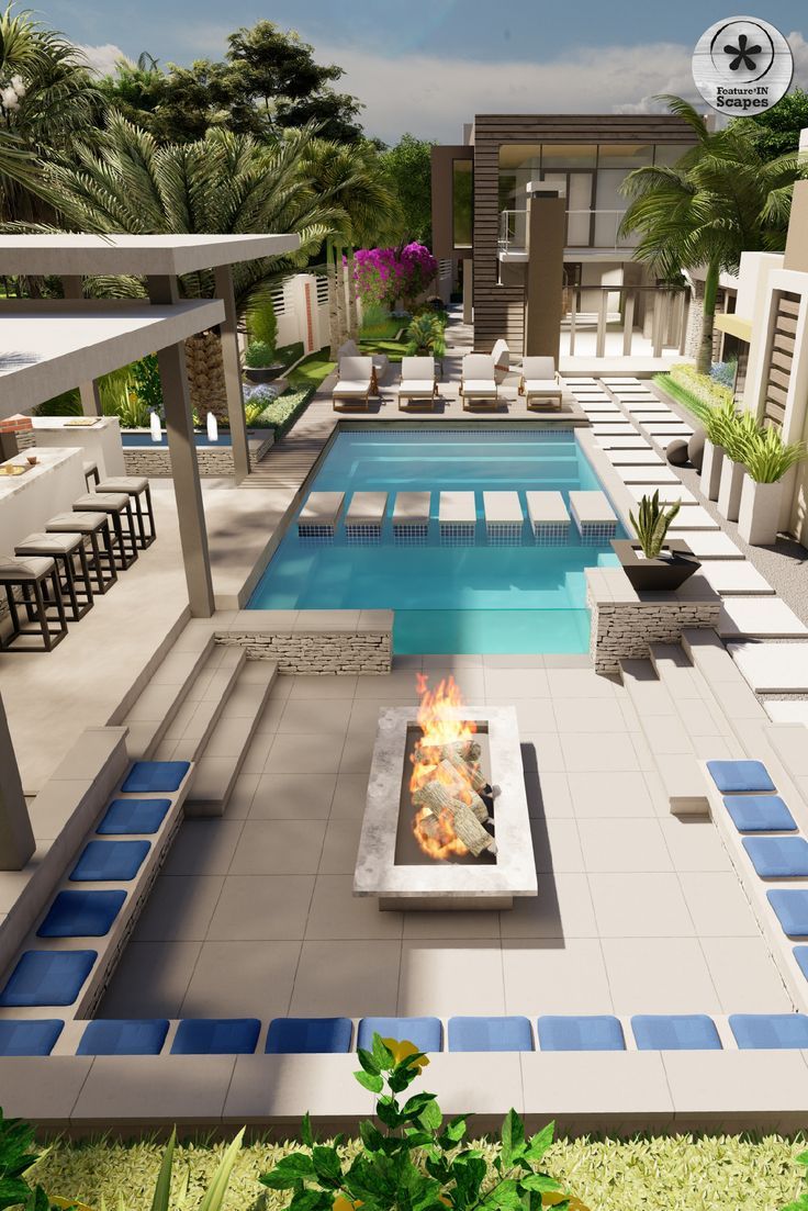 a fire pit sitting in the middle of a lush green yard next to a swimming pool