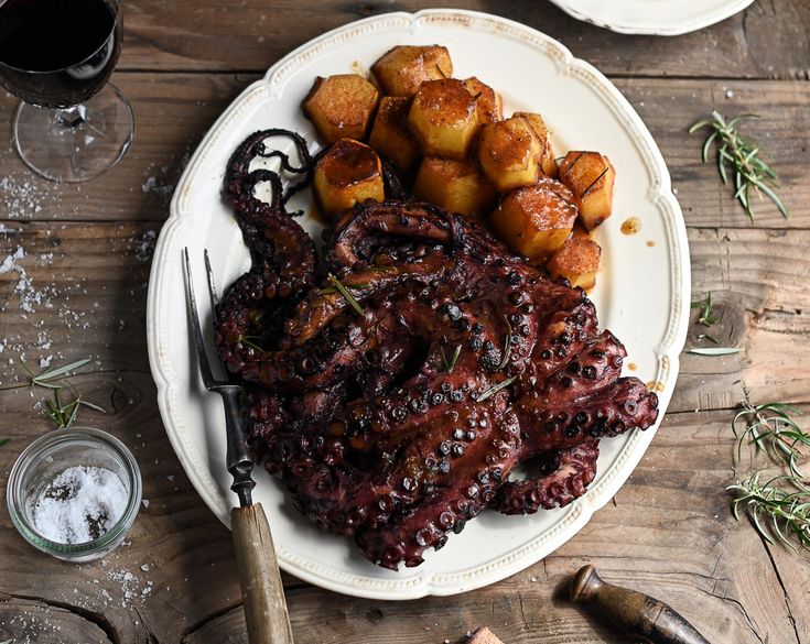 an octopus on a plate with potatoes and wine