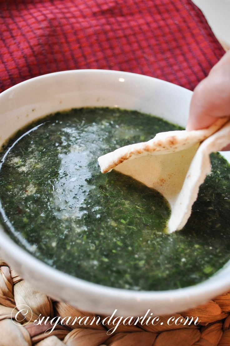 a person dipping some kind of sauce into a bowl with tortilla chips in it