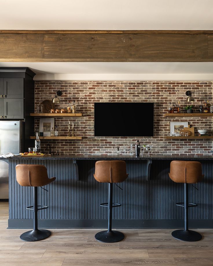 three stools in front of a bar with a flat screen tv on the wall