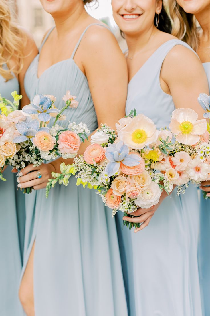 four bridesmaids in blue dresses holding bouquets