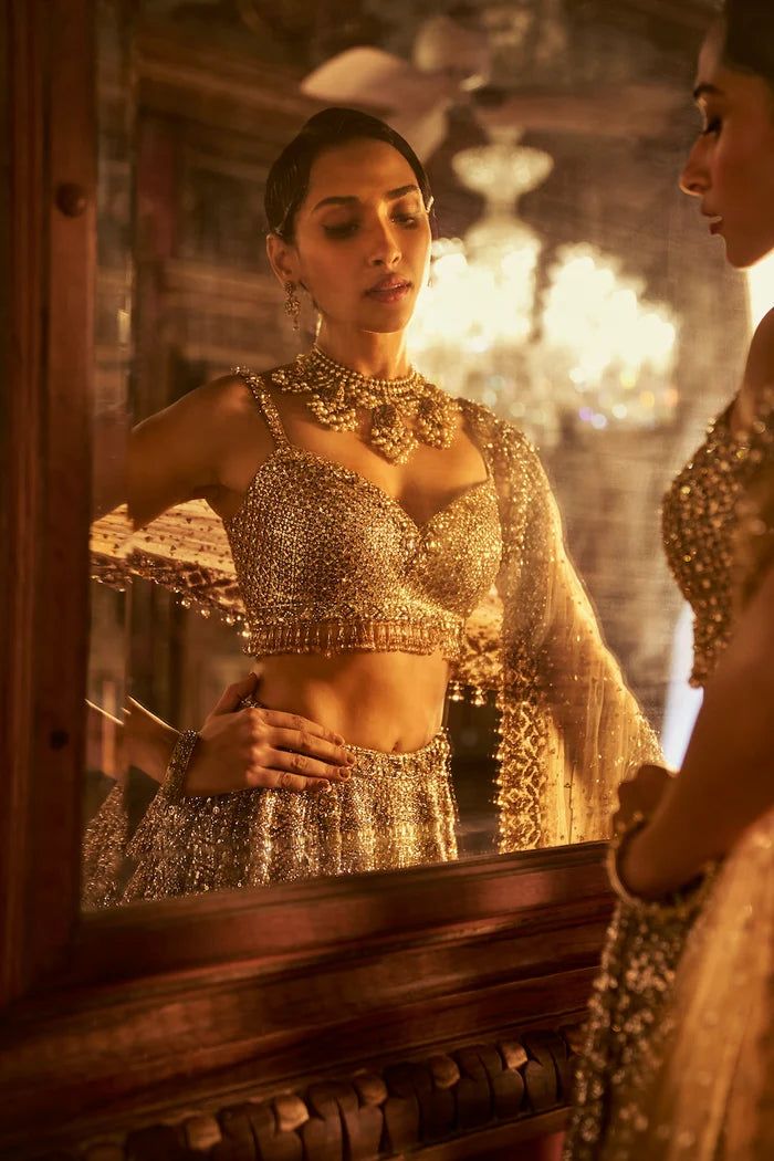 This antique gold lehenga set features intricate embroidered in sequin & crystal work The matching blouse shows tassels at the waist and t is paired with a matching net dupatta with border and tassels on all four sides.From Seema Gujral's Falaknuma collection. DELIVERY TIMEPlease allow 8-12 weeks for your outfit to arrive. FABRIC DETAILSNet Professional cleaning only. Sequin Lehenga, Gold Lehenga, Crystal Work, Net Dupatta, 12 Weeks, Gold Sequin, Professional Cleaning, Skirt Length, Antique Gold