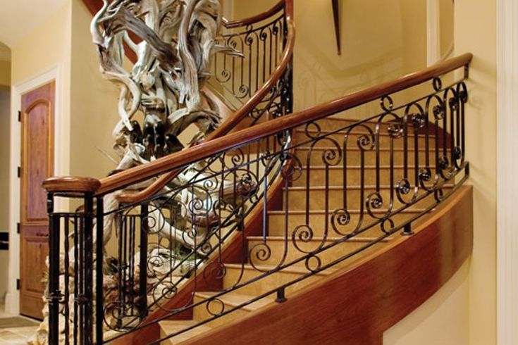 a spiral staircase with wrought iron railing and wood handrail