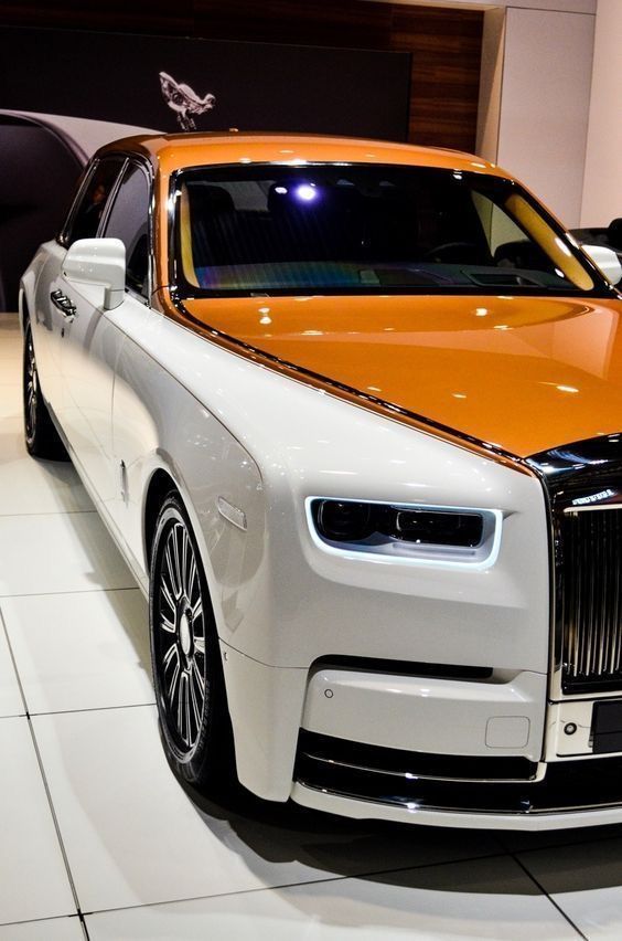 an orange and white car on display in a showroom with other cars behind it