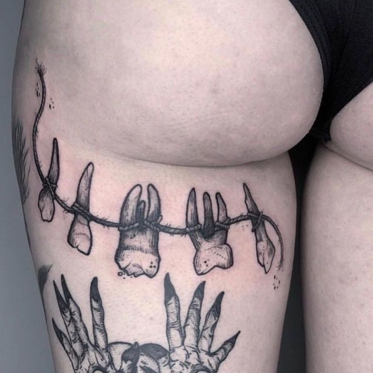 a woman's thigh with tattoos on her legs and hands hanging from the string