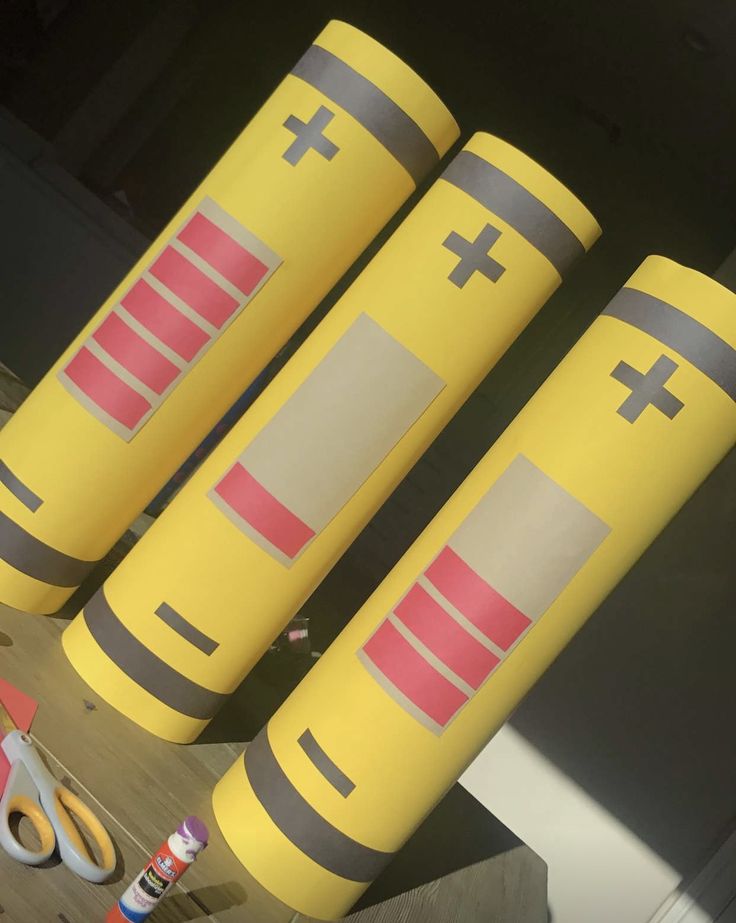 three yellow cylinders with crosses on them sitting next to scissors