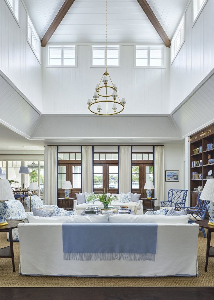 a living room filled with furniture and a chandelier hanging from the vaulted ceiling