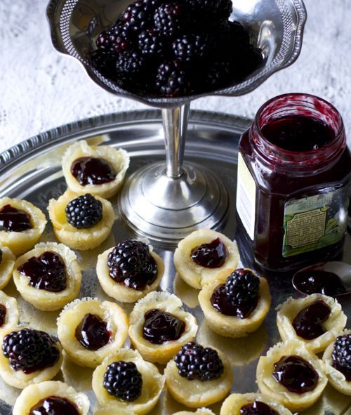 small pastries on a silver platter with jam in the jar next to them