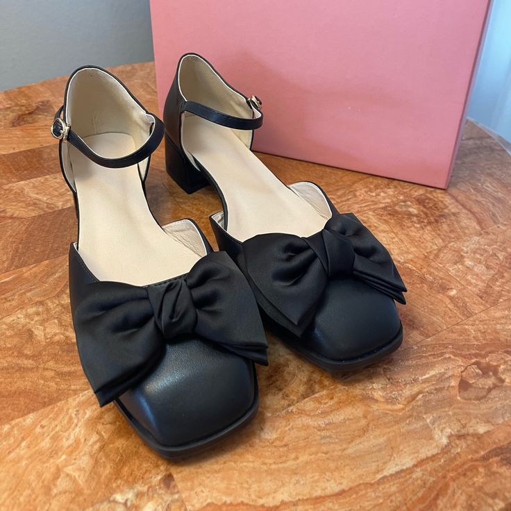 Product Description: Sophisticated Mary Jane Showcasing A Modern Square Toe With A Contrast Bow And A Dainty Ankle Strap With A Buckle Closure. 1.76'' Heel Buckle Closure Man-Made Upper Man-Made Lining Man-Made Footbed Man-Made Midsole Man-Made Sole Imported Black Heels For Office Spring Season, Black Office Heels For Spring, Black Low Heel Spring Heels, Black Low Heel Heels For Spring, Chic Black Heels With Bow, Black Block Heel With Bow, Black Bow Heels For Work, Chic Black Heels With Flat Heel, Chic Black Flat Heel Heels