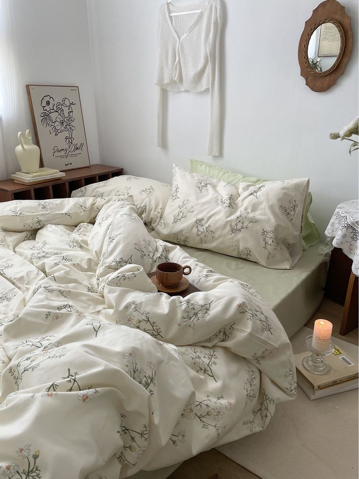 an unmade bed with white sheets and pillows in a bedroom next to a mirror