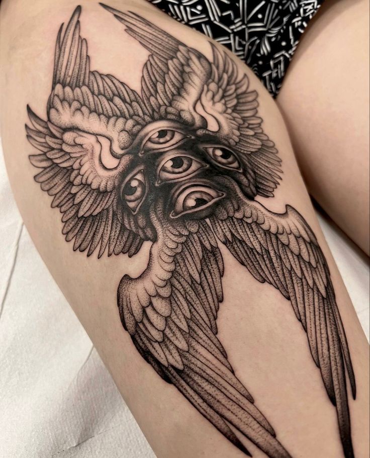 a woman's thigh with a black and white tattoo design on it, depicting a bird