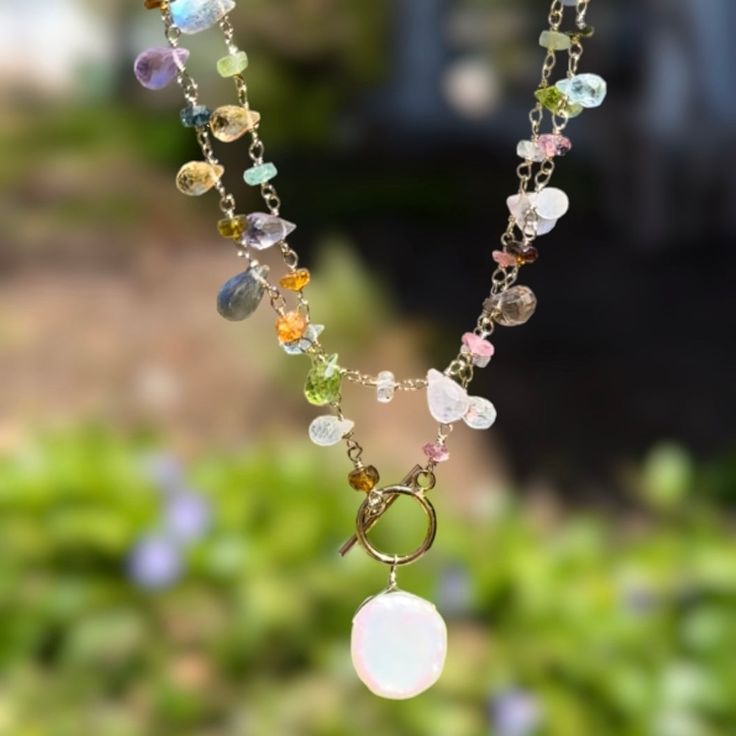 Semi-precious stones including garnet, rose quartz, citrine, peridot, sky blue topaz, amethyst, labradorite and moonstone are hand-wrapped in 14k gold dipped sterling silver with a keshi pearl charm.  Toggle closure designed to wear in front, 18" total length and layers beautifully with our Wildflower Choker.  Elegant, Spiritual Moonstone Jewelry With Gemstone Beads, Ethiopian Opal Gemstone Jewelry, Round Shape, Sterling Silver Gemstone Beads Jewelry For Healing, Yellow Gold Wire Wrapped Jewelry For Healing, Healing Sterling Silver Jewelry With Gemstone Beads, Healing Sterling Silver Gemstone Beads Jewelry, Yellow Gold Multi-stone Moonstone Jewelry, Elegant Multi-stone Healing Jewelry, Sterling Silver Lariat With Natural Stones