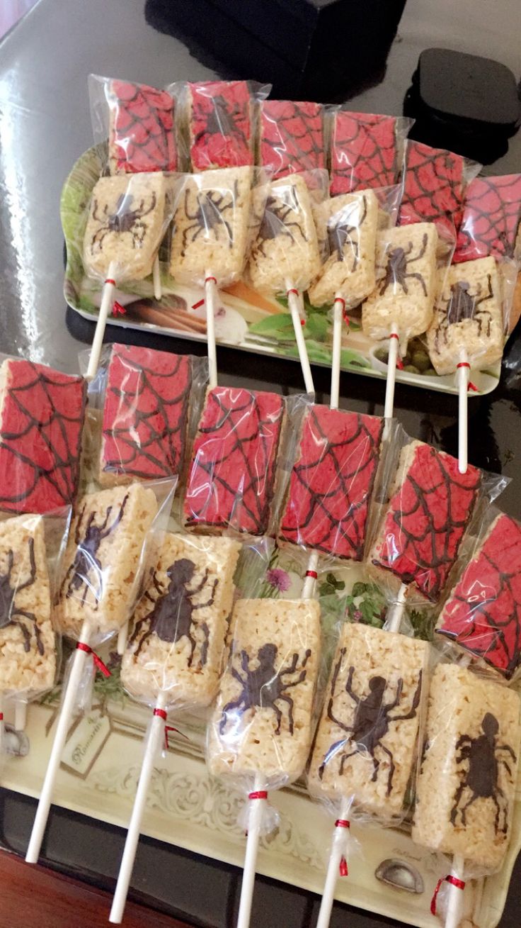 there are many desserts on the table with candy sticks in them and spider - man candies