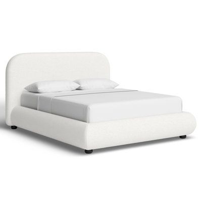 a white bed with two pillows on top of it and a night stand next to it