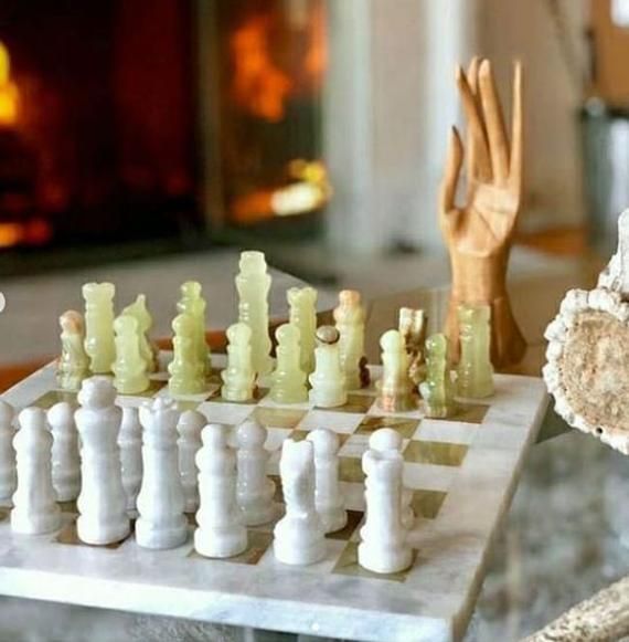 a wooden chess set sitting on top of a marble table next to a fire place