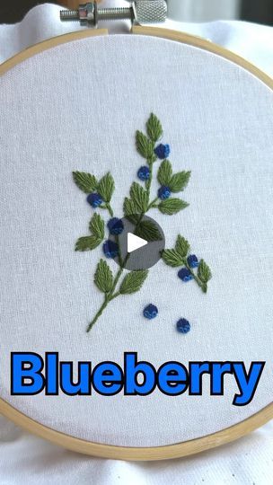 a blueberry embroidered onto a white fabric with the words blueberry on it in front of an embroidery hoop