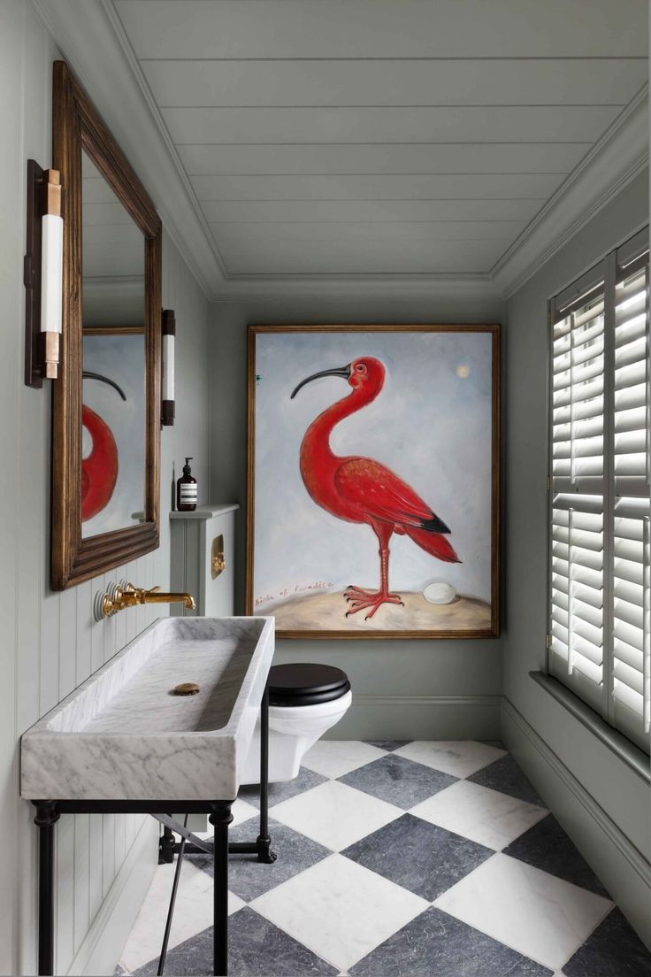 a bathroom with two paintings on the wall and a checkered tile floor, along with a pedestal sink