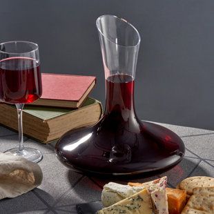 a glass of red wine next to some cheese and crackers on a table with books