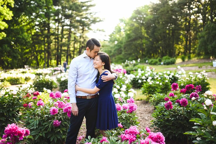 a man and woman standing next to each other in front of pink flowers on the ground