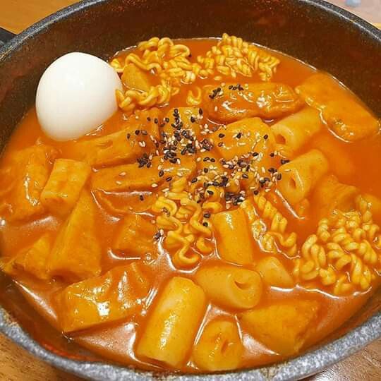 a bowl filled with noodles and an egg on top of it next to a wooden table