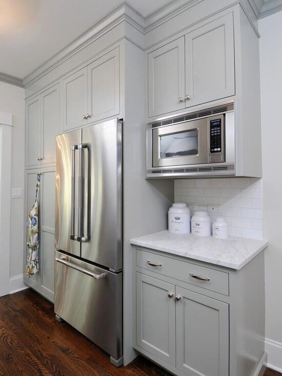 a kitchen with white cabinets and silver appliances