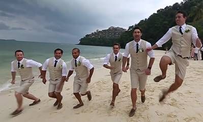 a group of men in white shirts and ties running on the beach