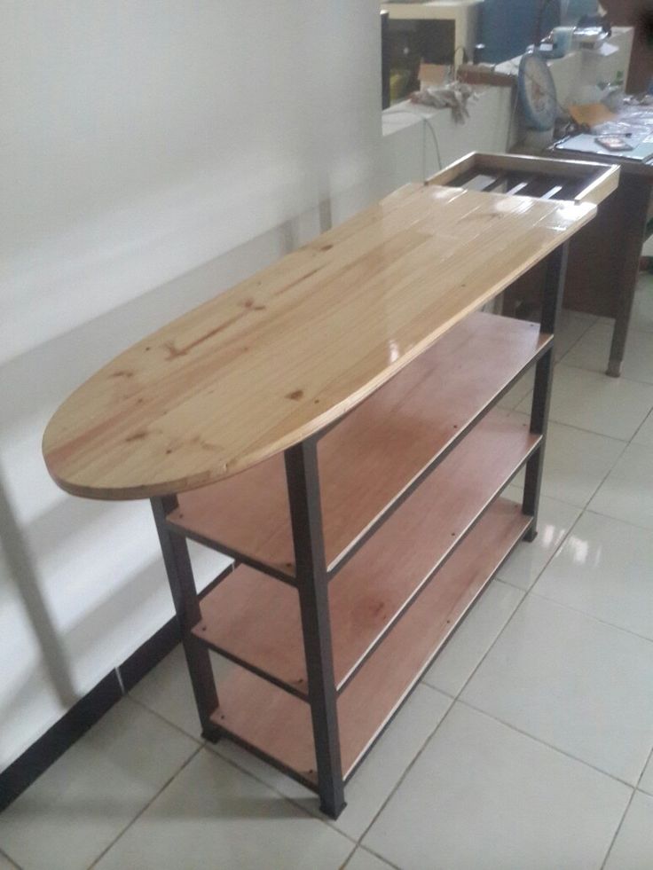 a wooden surfboard sitting on top of a shelf in a room with tile flooring