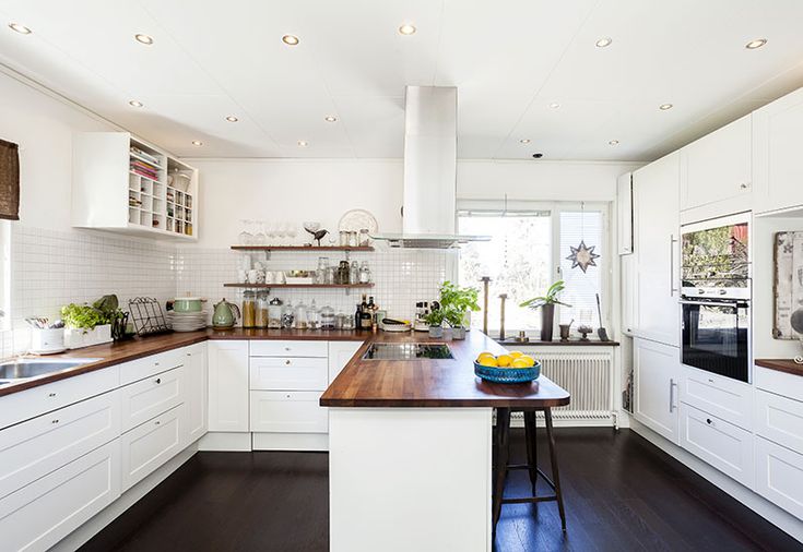 a kitchen with white cabinets and wooden counter tops, along with an island in the middle