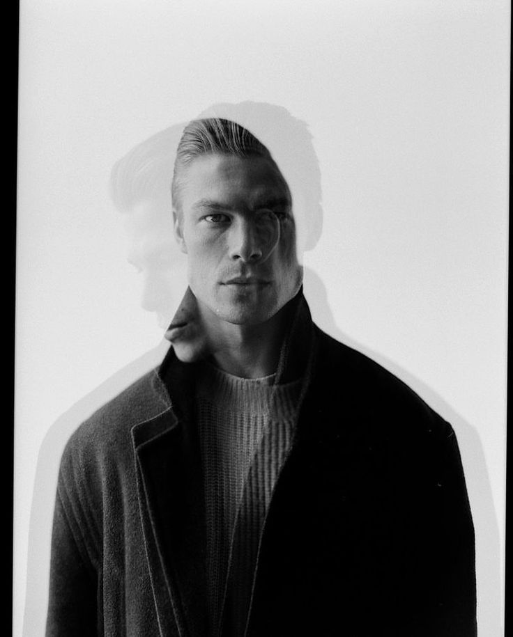 a black and white photo of a man in a jacket looking at the camera with a serious look on his face