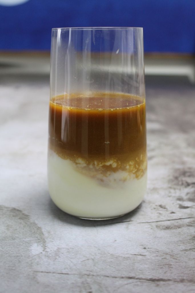 a glass filled with liquid sitting on top of a white counter next to a blue wall