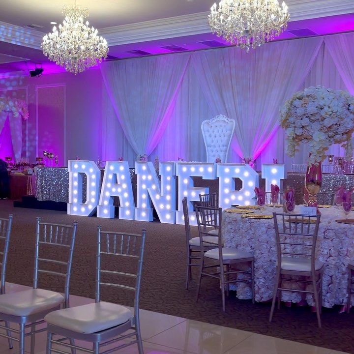 the dancer sign is lit up in purple and white lights for an elegant wedding reception