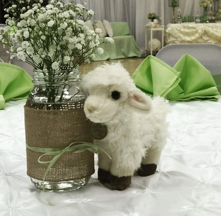 a stuffed lamb standing next to a vase with flowers in it