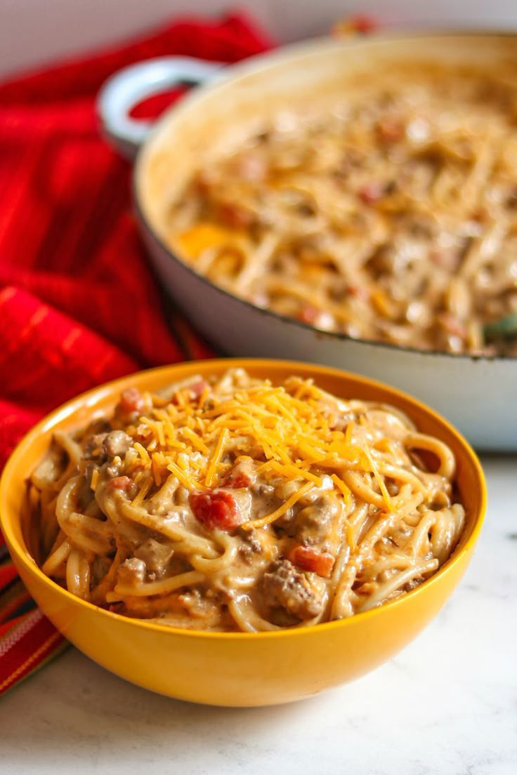 two yellow bowls filled with pasta and meat