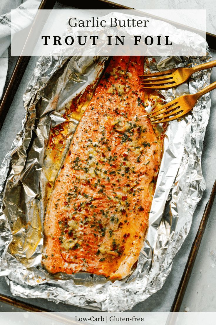 grilled salmon in foil with fork and knife on it, next to the title garlic butter trout in foil