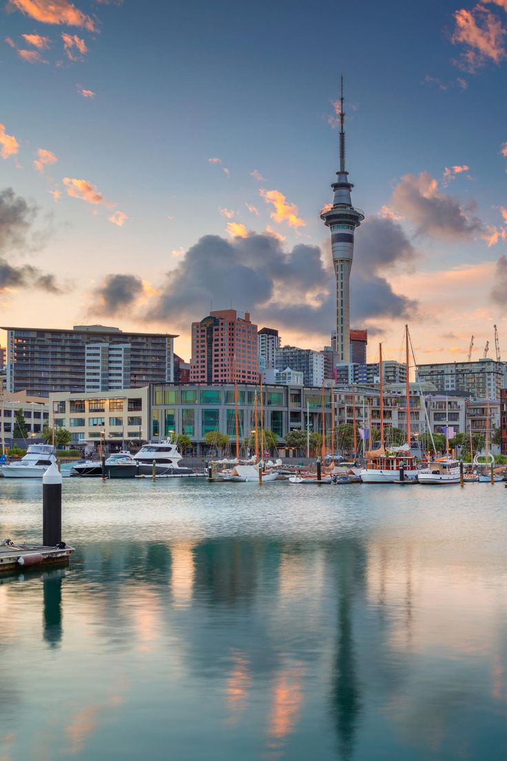 a city skyline with boats in the water and buildings on the other side at sunset