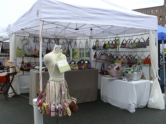 a white tent with bags and purses on display at an outdoor flea market in the city