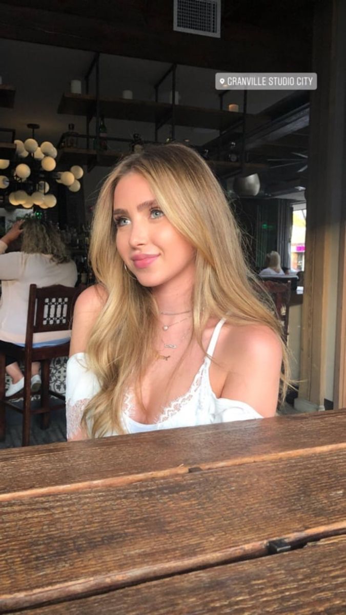 a beautiful blonde woman sitting at a wooden table