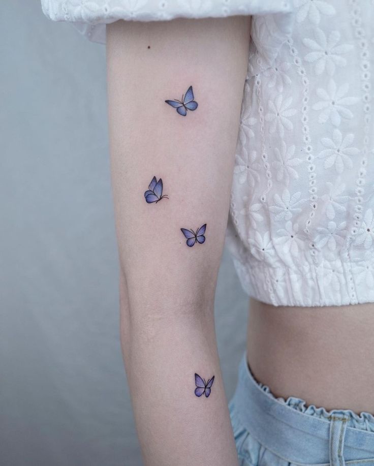 a woman's arm with blue butterflies on the back of her left arm and shoulder