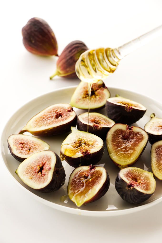 figs on a plate with honey being drizzled over them to eat