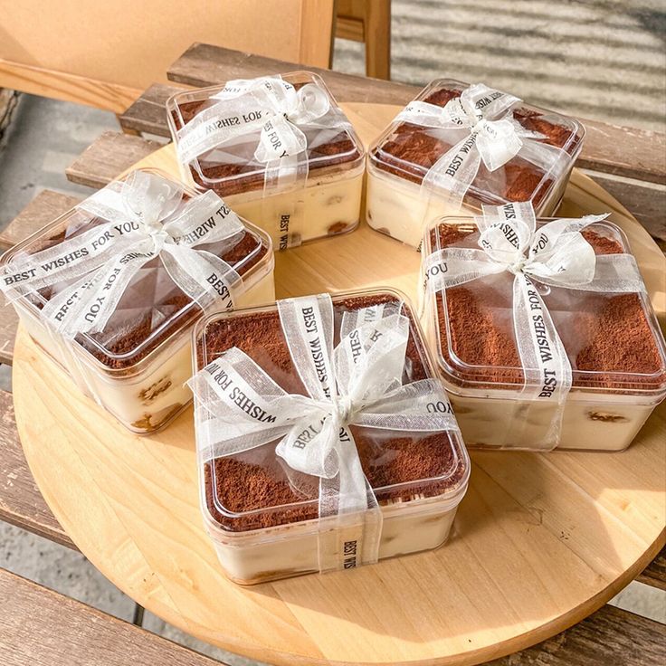 four brownies wrapped in plastic sitting on top of a wooden table