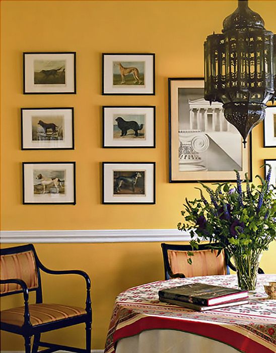 a dining room with yellow walls and pictures on the wall