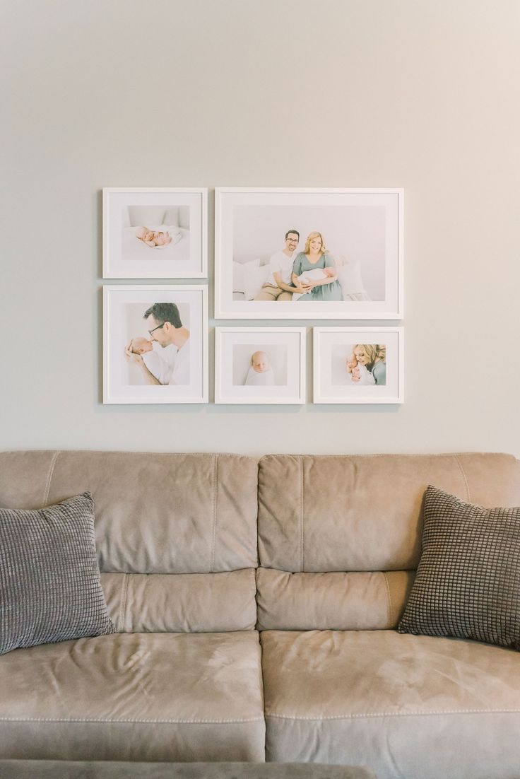 a living room with couches and pictures on the wall above them in white frames