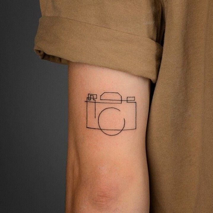 a person's arm with a camera tattoo on the left side of their arm