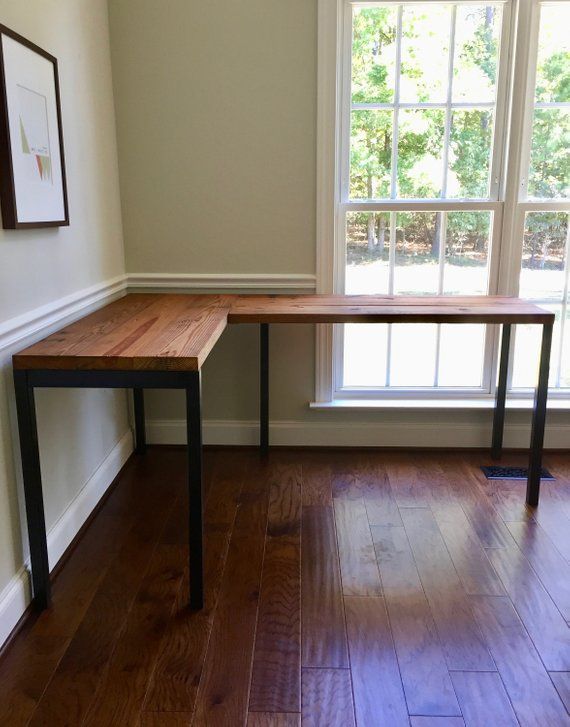 a wooden table sitting on top of a hard wood floor next to a large window