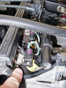 a hand is pointing at the wires in an engine compartment