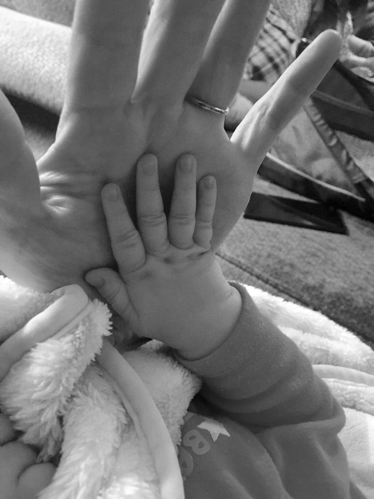 a person holding a baby's hand in the air with both hands on top of each other