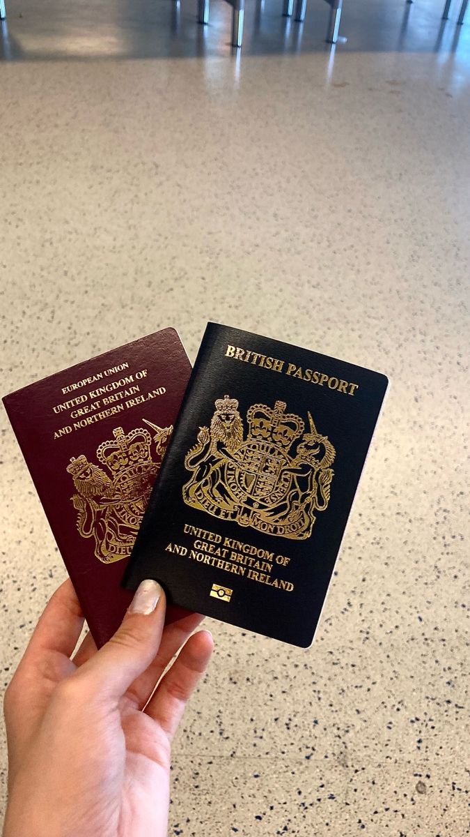 a hand holding two british passport cards in an airport