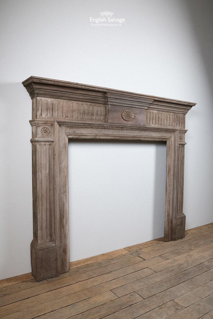 an old fireplace in the corner of a room with wood flooring and white walls