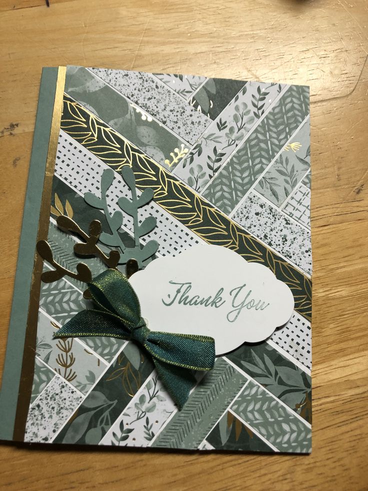 a thank you card with a green bow on it sitting on top of a wooden table