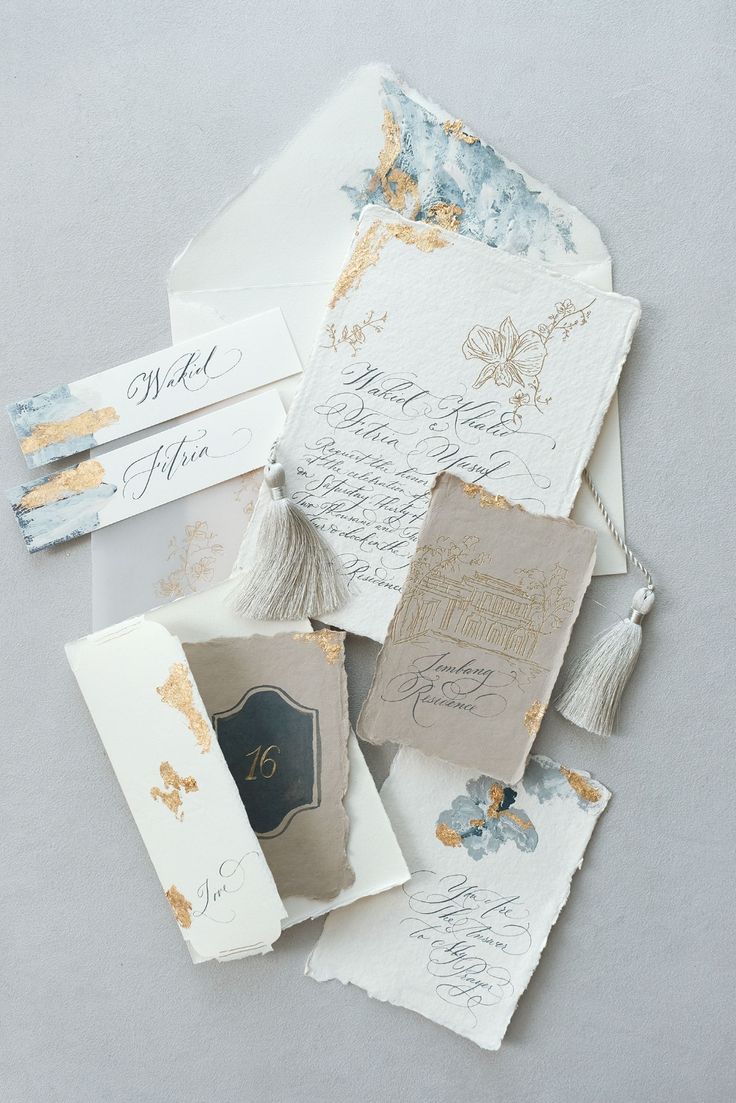 wedding stationery and envelopes laid out on top of each other with gold foil